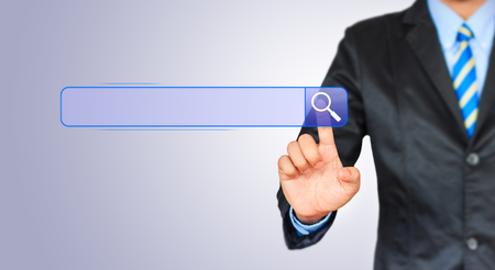 Business man pushing search botton on a touch screen interfaceの写真素材