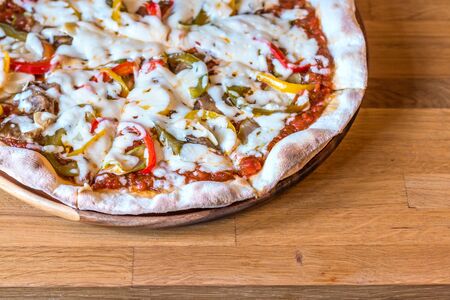 Hot pizza with melting cheese on a wooden table