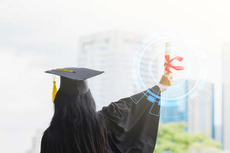 Happy graduate young Asian woman in cap and gown holding a certificated in handの写真素材