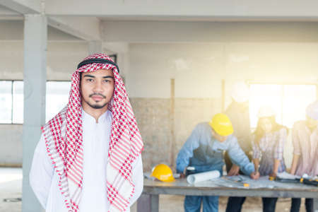 Arab engineer with Group of engineer background, They are checking the blueprint and talking about construction project with commitment to success at construction siteの写真素材