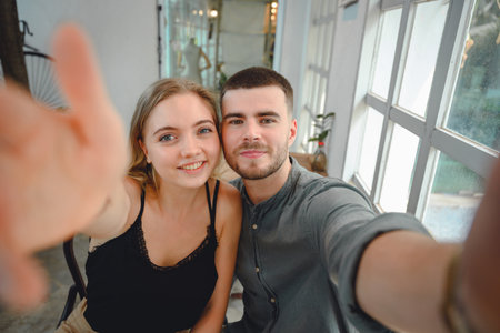 A young couple with a comfortable lifestyle. Young couple looking at selfie camera Two Caucasian...