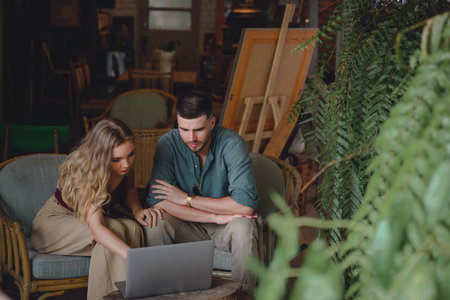 A young couple with a comfortable lifestyle. Young couple sitting and talking and making plans working on a laptop computer in her studioの写真素材