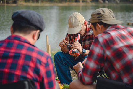 man with friends Smoking marijuana with a marijuana bong and blowing smoke sitting on a camping chair Lawn on vacation Male tourists smoke marijuana from bongs or pipes legallyの写真素材
