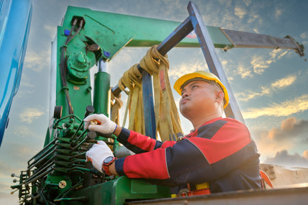Asian male worker Worker hand operating crane on construction site to lift heavy construction equipment at the construction siteの写真素材