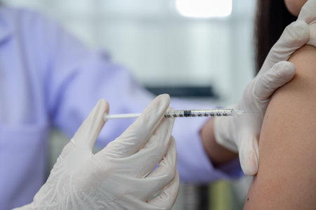 Closeup of female doctor hands wearing medical gloves vaccinations or injections in the arm to protect against viruses and influenzaの写真素材