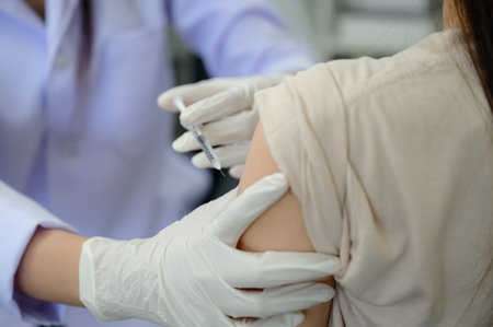 Closeup of doctor hand doing vaccination or injection on patient's shoulder Influenza vaccination in the arm wearing medical glovesの写真素材