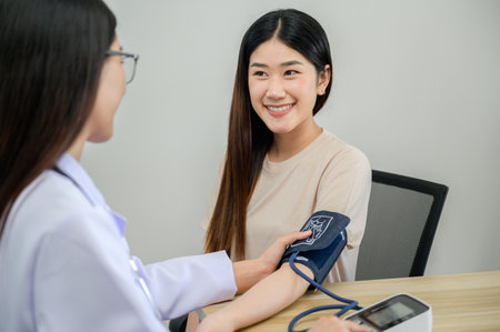 Asian female doctor measuring heart rate and blood pressure while taking care of beautiful asian...