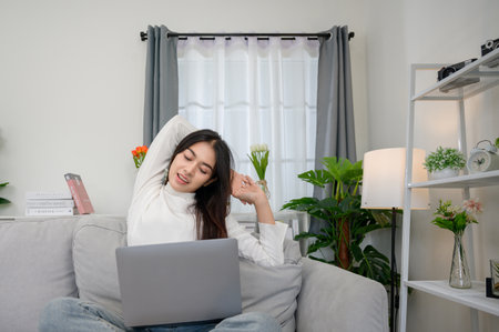 Asian woman working from home using laptop Businesswoman twisted because she is tired from working from home.の写真素材