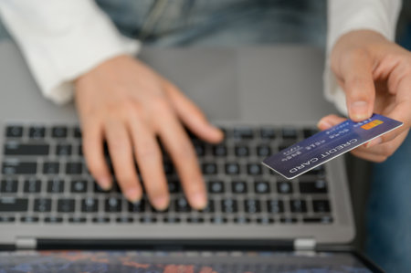 close up young woman Hand holding credit card and using laptop computer Happy businesswoman sitting at home, online shopping, e-commerce, spending money, work from home concept.の写真素材