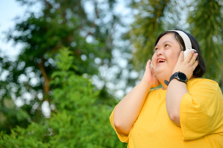 Asian girl with Down syndrome wearing headphones Smiling with happiness in the park in the middle of natureの写真素材