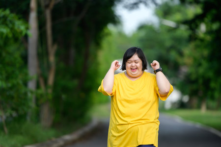 Asian woman with down syndrome smiling happy Fat young woman with down syndrome exercising in the park in the middle of natureの写真素材