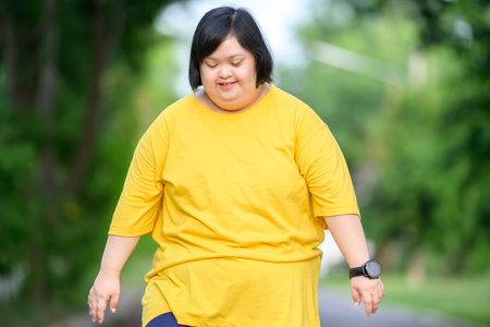young woman with down syndrome exercising by walking to burn fat and running slowly fat young woman exercising in the park in the middle of natureの写真素材