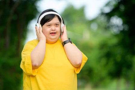Asian girl with Down syndrome wearing headphones Smiling with happiness in the park in the middle of natureの写真素材