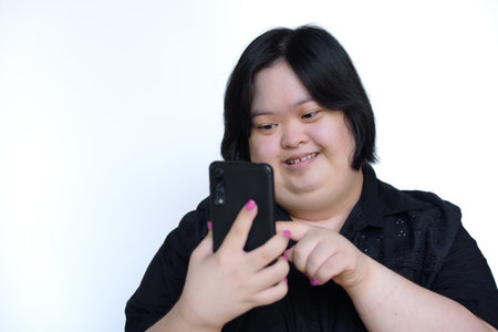 Asian fat girl with disabilities or children with Down syndrome Playing on the phone and smiling happily on white background. Concept: Down syndrome.の写真素材