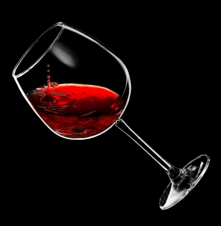 drops of red wine dripping into a glassの写真素材