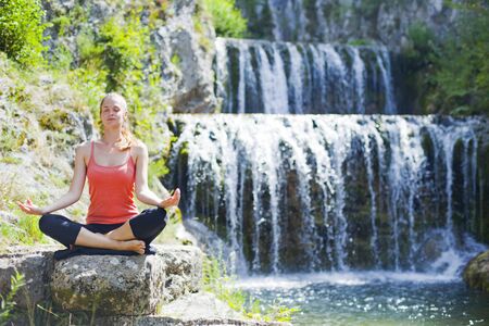 young woman sitting outdoors in yoga positionの写真素材