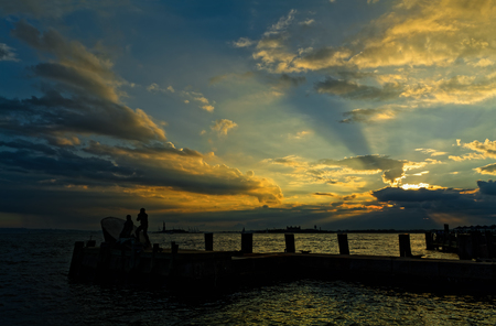 River Hudson in New York City, USA at sunset, with Liberty Island and Ellis Island silhouettes in the distance.の写真素材