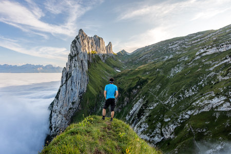 Hiking in Switzerland. Man walking on the mountain trail. Fog in the valley.の写真素材