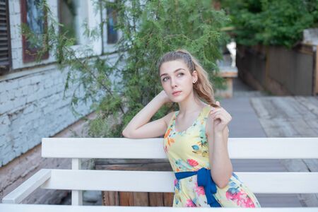 a young girl with long white curls in a dress walks through the old town in the summer. girl in a...