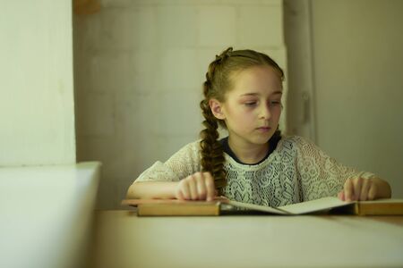 Pupil in school uniform with braids. Girl schoolgirl at school with books in school uniform. Training. Knowledge. 4th grade student. Beautiful little girl with light brown hair. Back to schoolの写真素材