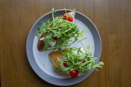 Fresh homemade crispy Italian antipasto called Bruschetta topped with tomato, garlic and basil on a plate and a wooden table. Food in the cafe. Vegetarian food. Tasty and healthy. White breadの写真素材