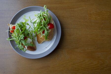 Fresh homemade crispy Italian antipasto called Bruschetta topped with tomato, garlic and basil on a plate and a wooden table. Food in the cafe. Vegetarian food. Tasty and healthy. White breadの写真素材