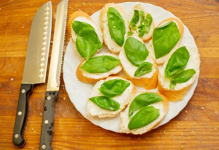 Cook smears cottage cheese on bread. Male hands spread soft cheese on french bread and spread basil. Vegetarian sandwiches. Healthy food. Healthy lifestyle. Summer foodの写真素材