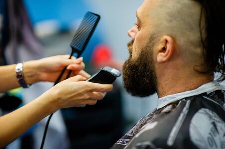 Hipster client visiting barber shop. Mens fashion. Bearded man after barber shop. Man hipster having barber shave barbershop hair machine. fashionable haircut, rear view. Weave braids.の写真素材