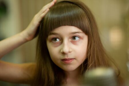 Hairdresser making a hair style to cute little girl. The girl cuts off the bangs. Work hairdresser....