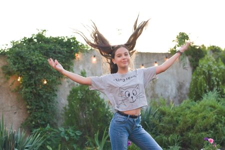 Yong pretty woman does exercises in a park. Beautiful teen girl in a gray T-shirt and jeans on...