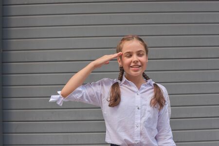 close up portrait of little beautiful stylish kid girl near gray wall as background. White blouse,...
