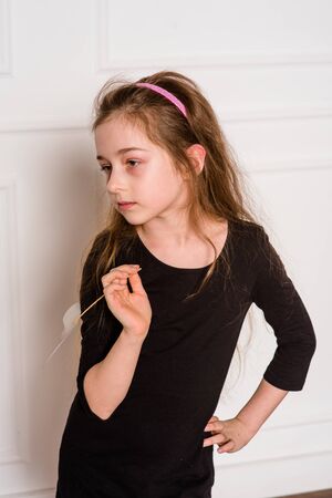 little fashion model in dress photo in photostudio backstage. A child of a girl of 8-9 years old is posing as an adult. Long hair. Modern children. Schoolgirl on a photo shoot.