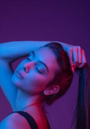 Very beautiful girl. Gorgeous brunette with plump natural lips. Portrait of a girl in the studio with color filters. Portrait, fashion, beauty, glow. Perfect profile of an interesting woman. Closed.の写真素材