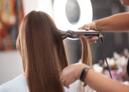 Make up. A series of photos of a model by a makeup artist. Beautiful girl with long hair at the stylist's hairstyle. Backstage makeup artist works in her office. Beauty saloon. Girl straighten hairの写真素材
