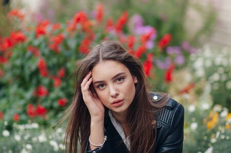 young girl in a black leather jacket stands on the background of a city street.Girl in a leather...