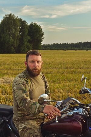Motorcyclist racing his motorcycle down straight country road going a high speed at sunset. Military...