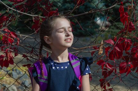 Girl with beautiful hair on a background of nature. Shy teenager in the sun. Schoolgirl on a...