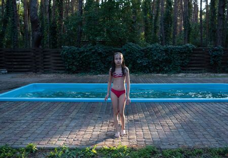 Cute baby have fun on vacation. Children bathe in pool. Little child enjoying pool indoors. girl bathes in the pool. Pool in the forest. Rest in the woods of a child with his family.Girl 9 years oldの写真素材