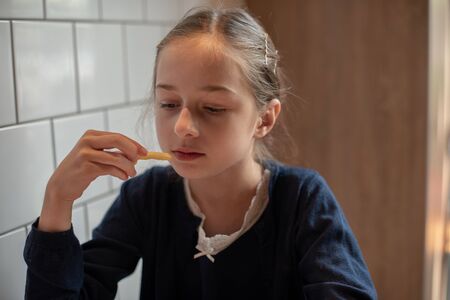Happy teen girl eating a burger and french fries. Schoolgirl eating a burger.A girl of 9 years old...