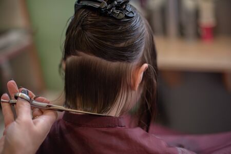 Stylist hairdresser makes a hairstyle for a cute little girl in a beauty salon.Hairdressing, hair...