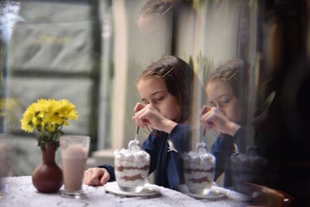 Little girl drinking hot chocolate in a cafe. schoolgirl drinks cocoa in a cafe. girl after classes...