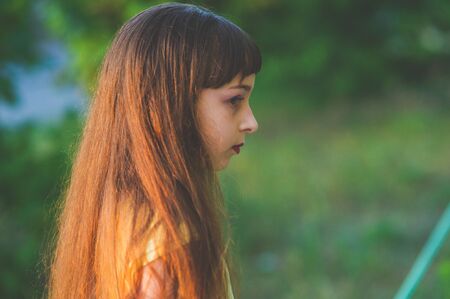 Girl walks in the woods. Girl walking in the park.A little girl of 9 years went for a walk on the street in summer or early autumn. Schoolgirl walking after school. Girl with long hair in a dressの写真素材
