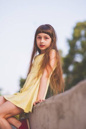 Girl walks in the woods. Girl walking in the park.A little girl of 9 years went for a walk on the street in summer or early autumn. Schoolgirl walking after school. Girl with long hair in a dressの写真素材