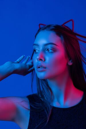 Funny girl represents as small cat. Woman with bright makeup hairstyle of girl with cat ears having fun. on blue background isolated. Brunette girl cat. Girl with fluffy red cat head in studioの写真素材