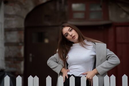 girl stands on the background of a city street. Girl in a gray coat. A series of photos with a...