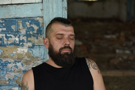 Close up of long beard and mustache of bearded man.Man in black with a beard. A 40-year-old man with a black beard against the background of an old wall in blue. A brutal and handsome guy.の写真素材