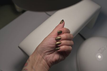 Woman hands receiving a manicure in beauty salon. Nail filing. Close up, selective focus.Female hands in the process of manicure, cutting of the cuticle, correction of the shape of the nail plateの写真素材