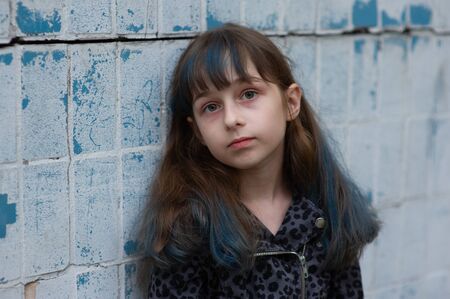 Portrait of nine year old girl. The child is walking in the fresh air. Teenager with blue strands on...