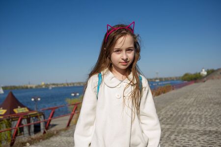 The girl put a piece of jewelry on the head of a cat's ears. Hoop cat ears. Girl with blond long...