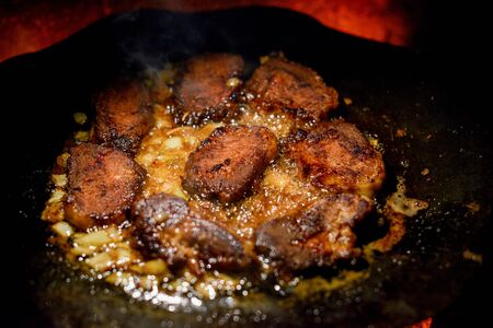 Cutlets pan fried in the fire. pan is also cooking meat. Pork chunks of meat are cooked on a bonfire on a disc from a harrow. Chunks of meat are fried with onions. Tasty dinner or lunch. Street foodの写真素材